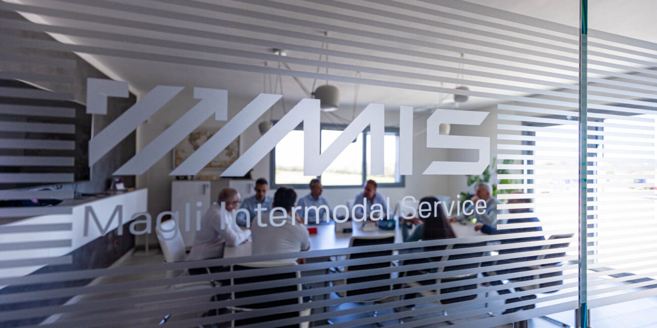 Il team MIS nella sede aziendale, dietro il marchio Magli Intermodal Service